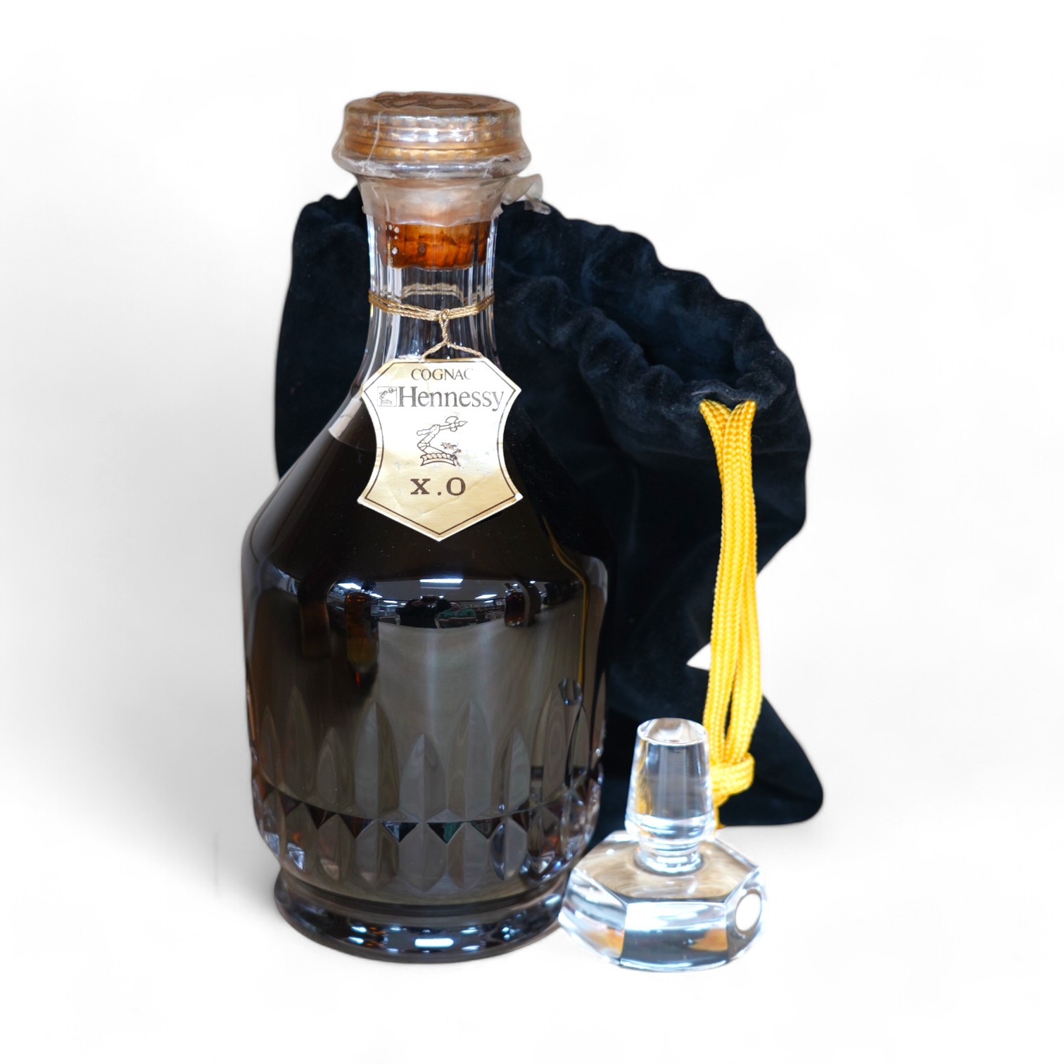 A bottle of Hennessy XO Cognac in a Baccarat crystal decanter, with separate glass stopper, contained with a drawstring bag. Condition - good